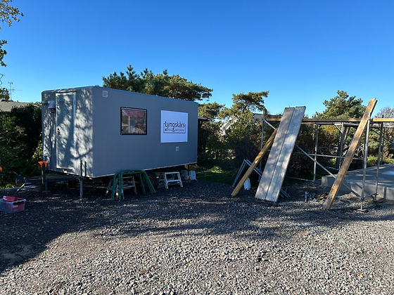 Byggarbetsplats med byggbod, material och ställning